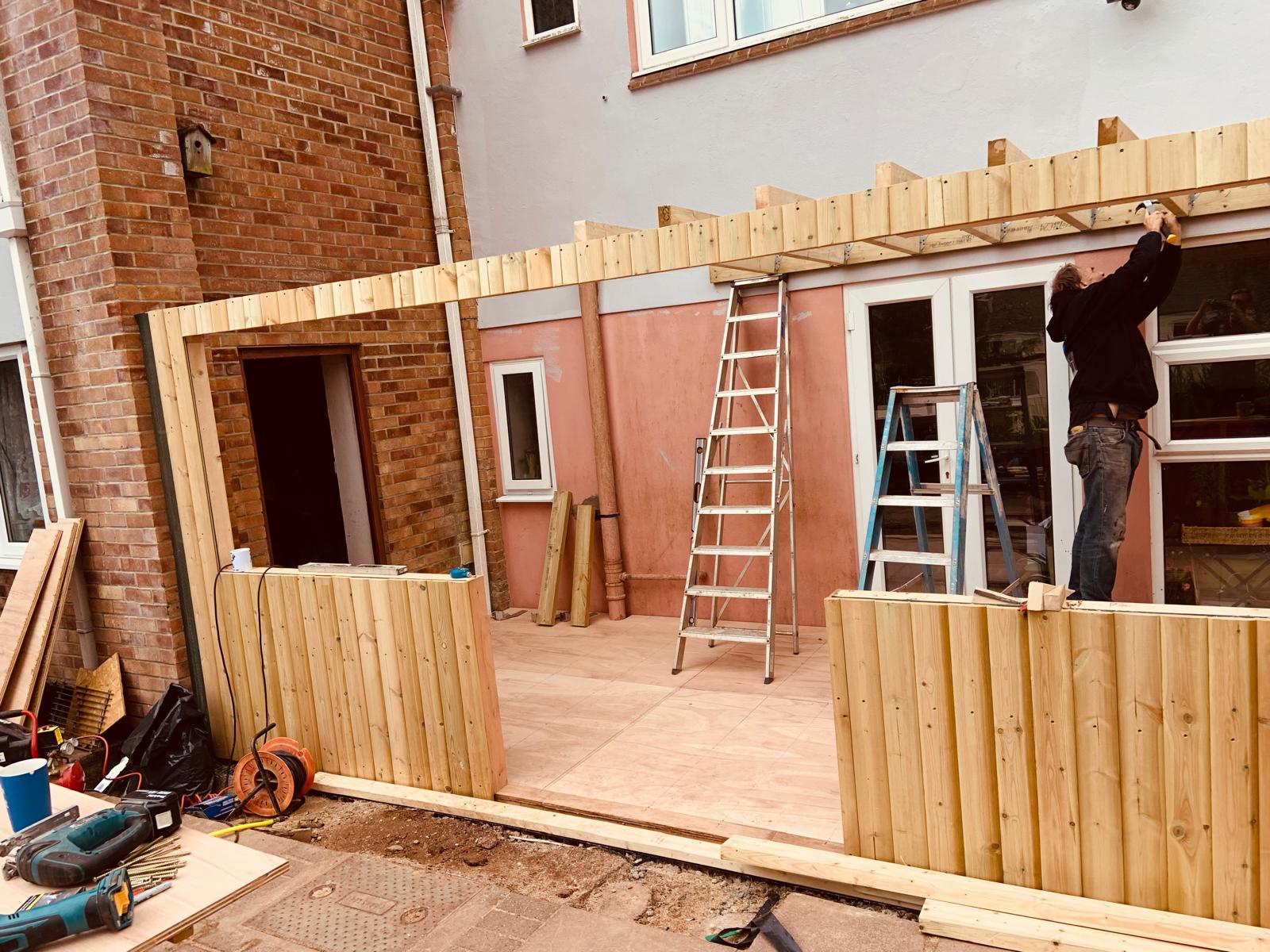 Timber Porches Timber frame extension under construction against a house
